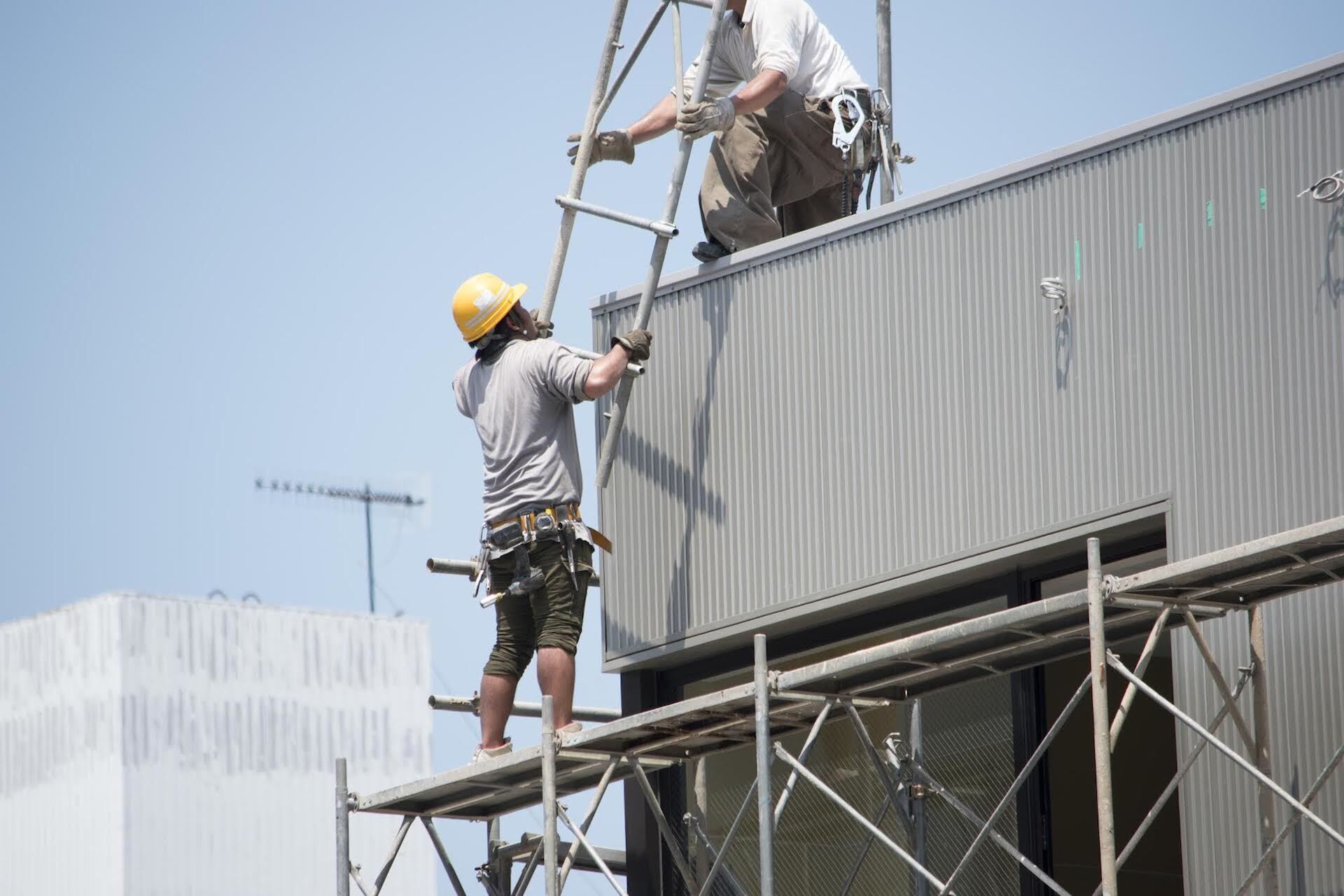 上から下に足場を運ぶスタッフ